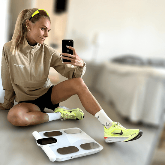 Laura i løbetøj med sin Kropsscanner Pro, som hun bruger til at måle fedtprocent, muskelmasse og kropssammensætning. Hun er aktiv løber og glad for, hvordan scanneren hjælper hende med at følge sin træning og sundhedsudvikling